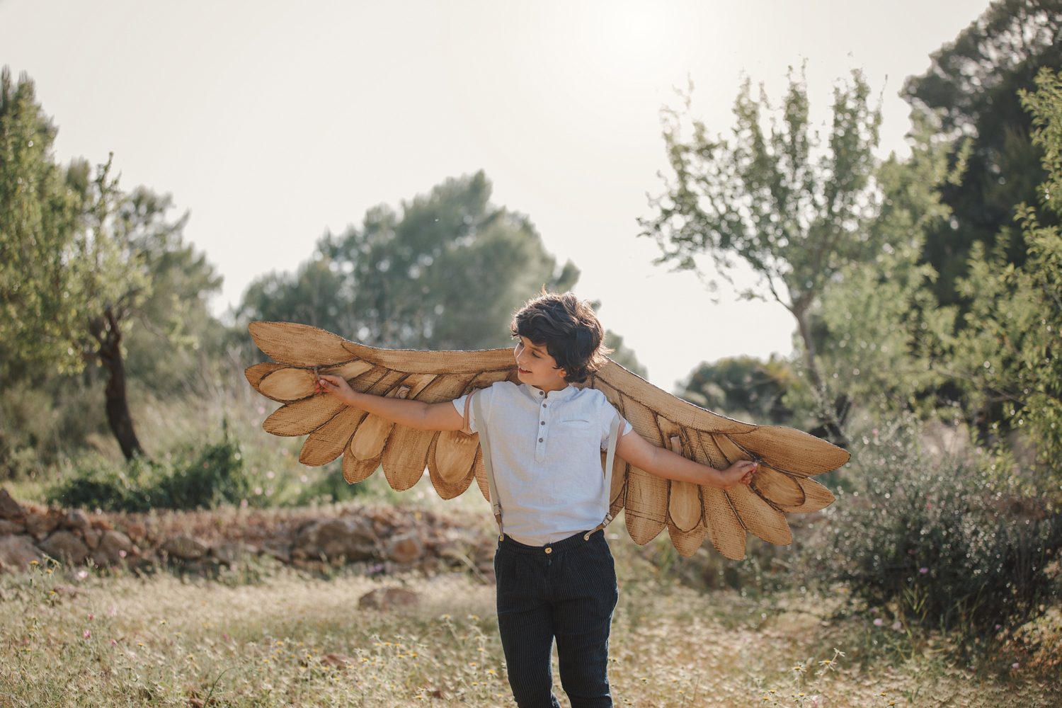Niño con alas en bosque, sesión fantasía exterior